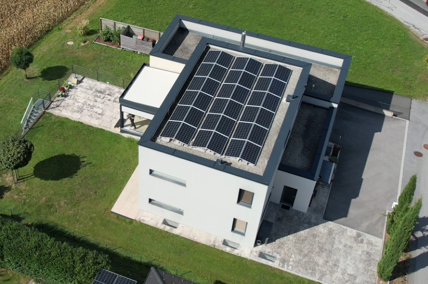 Luftaufnahme eines weißen Flachdachhauses mit aufgeständerten Photovoltaik-Modulen