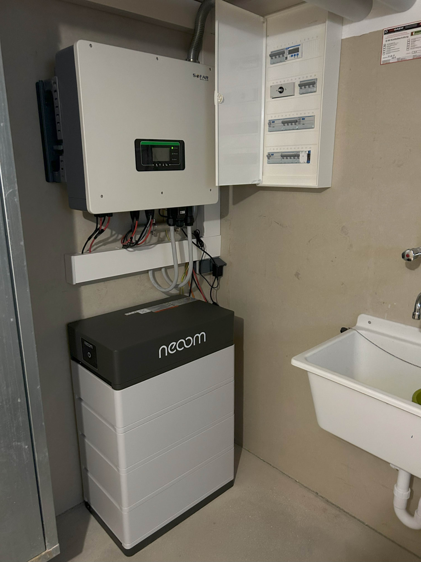 Wechselrichter, Verteilerkasten und ein kompakter Batteriespeicher an einer Kellerwand montiert